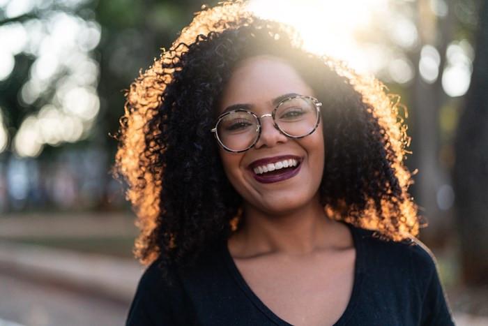 Leende ung kvinna med glasögon som här skall symbolisera glädjen över att själv kunna påverka sitt boende genom styrelsearbete när man väljer att köpa  nyproducerad bostadsrätt.