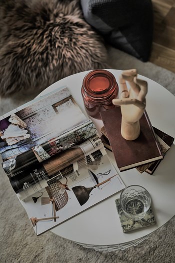 Ett stilleben med inredningstidning ljuslykta och böcker på ett soffbord som symboliserar de genomtänkta och harmoniska inredningen i våra nyproducerade lägenheter i stockholm göteborg och malmö