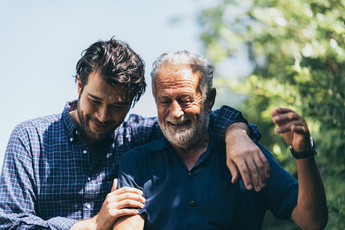 Yngre man håller armen om äldre man utomhus, skall symbolisera umgänge över åldersgränserna i en bostadsrättsförening.